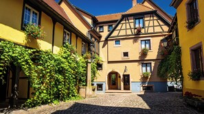 Une rue pavée bordée de bâtiments européens traditionnels, avec une porte en bois et des jardinières fleuries.