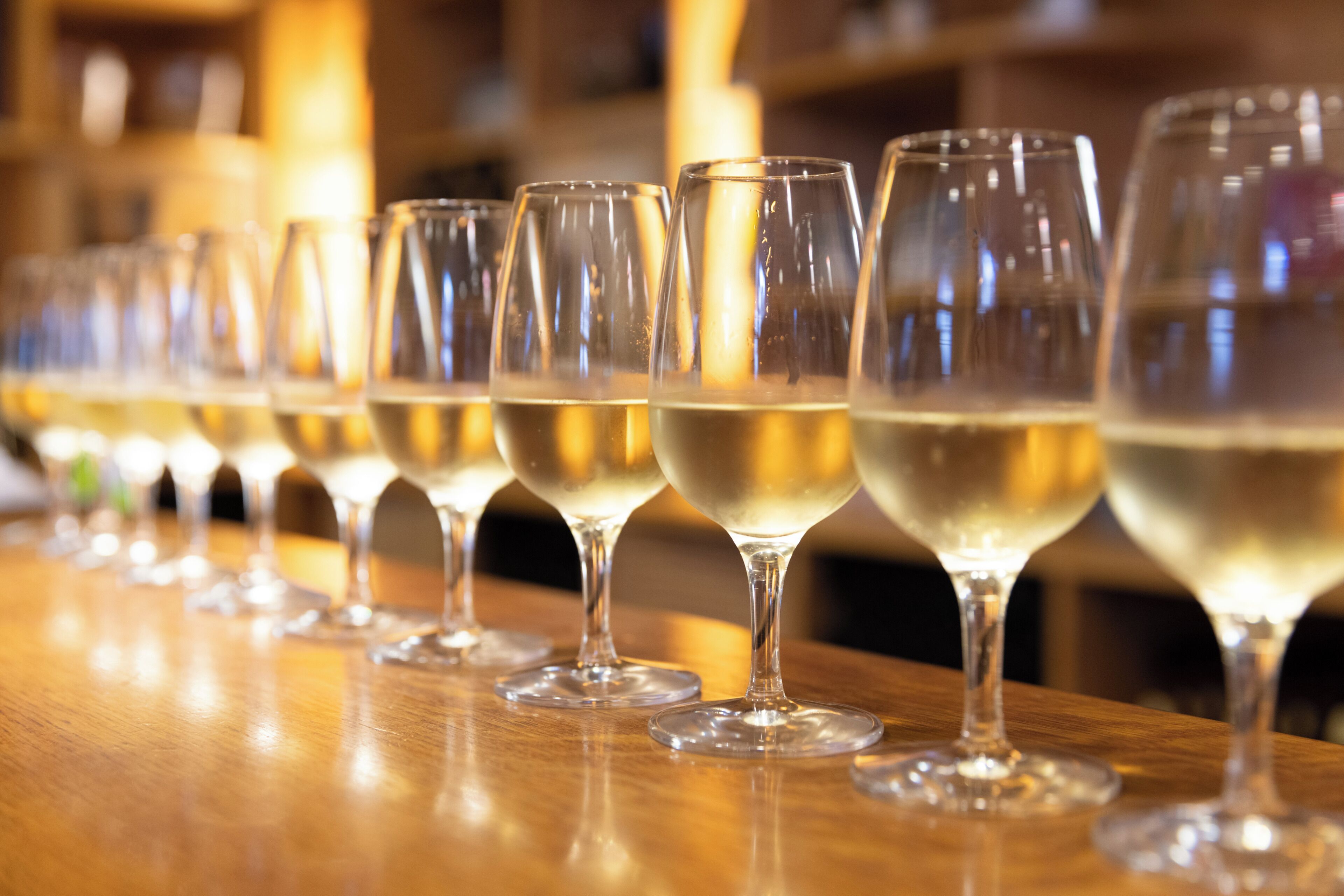 A row of empty wine glasses on a wooden bar counter.