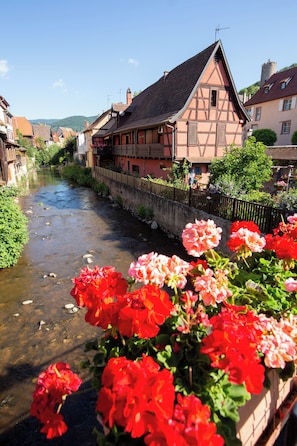 Une rivière traverse une ville où l’on trouve des maisons traditionnelles à colombages et un pont.