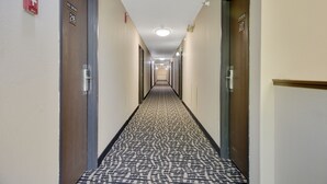 A hotel hallway with patterned carpet, doors numbered 216 and 217, and a fire alarm on the wall. - North Town Inn & Suites (Finlayson)