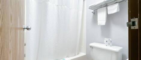 Une salle de bain avec une baignoire, des toilettes et une étagère avec des serviettes.