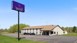 A North Town Inn & Suites with a parking lot and a building with a sloped roof. - North Town Inn & Suites (Finlayson)