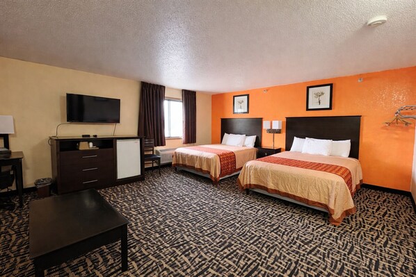 A hotel room with two beds, a TV, a desk, and a dresser. - North Town Inn & Suites (Finlayson)