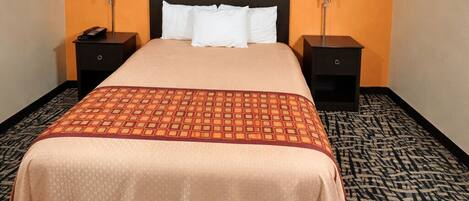Una habitación de hotel con una cama, dos mesitas de noche, un cabecero y una alfombra estampada.