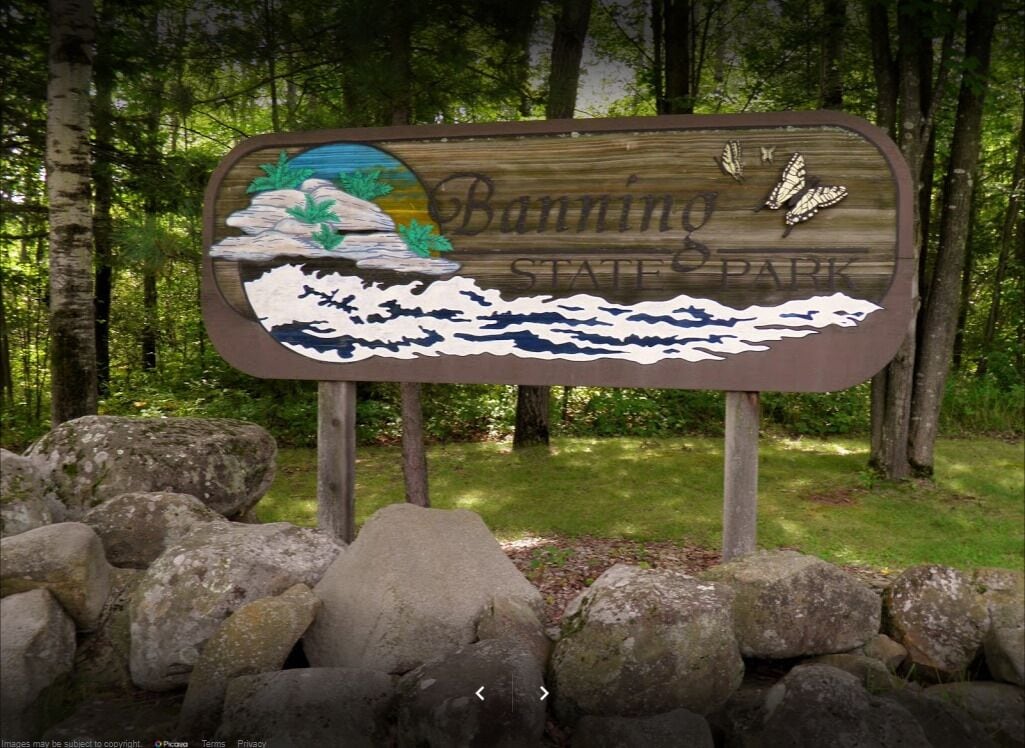 Een houten bord met de tekst 'Banning State Park' en een illustratie van een berglandschap.