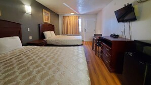 A hotel room with two beds, a desk, a chair, a dresser, a television, and a door. - Welcome Inn (Dallas)