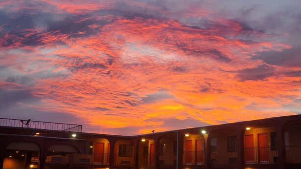 A building with multiple rooms, each with a door and windows, under a sunset sky. - Welcome Inn (Dallas)