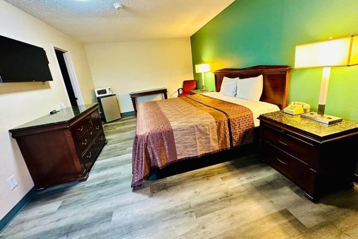 Hotelkamer met een bed, nachtkastjes, een bureau, een stoel, een televisie, een magnetron en een groene accentmuur.