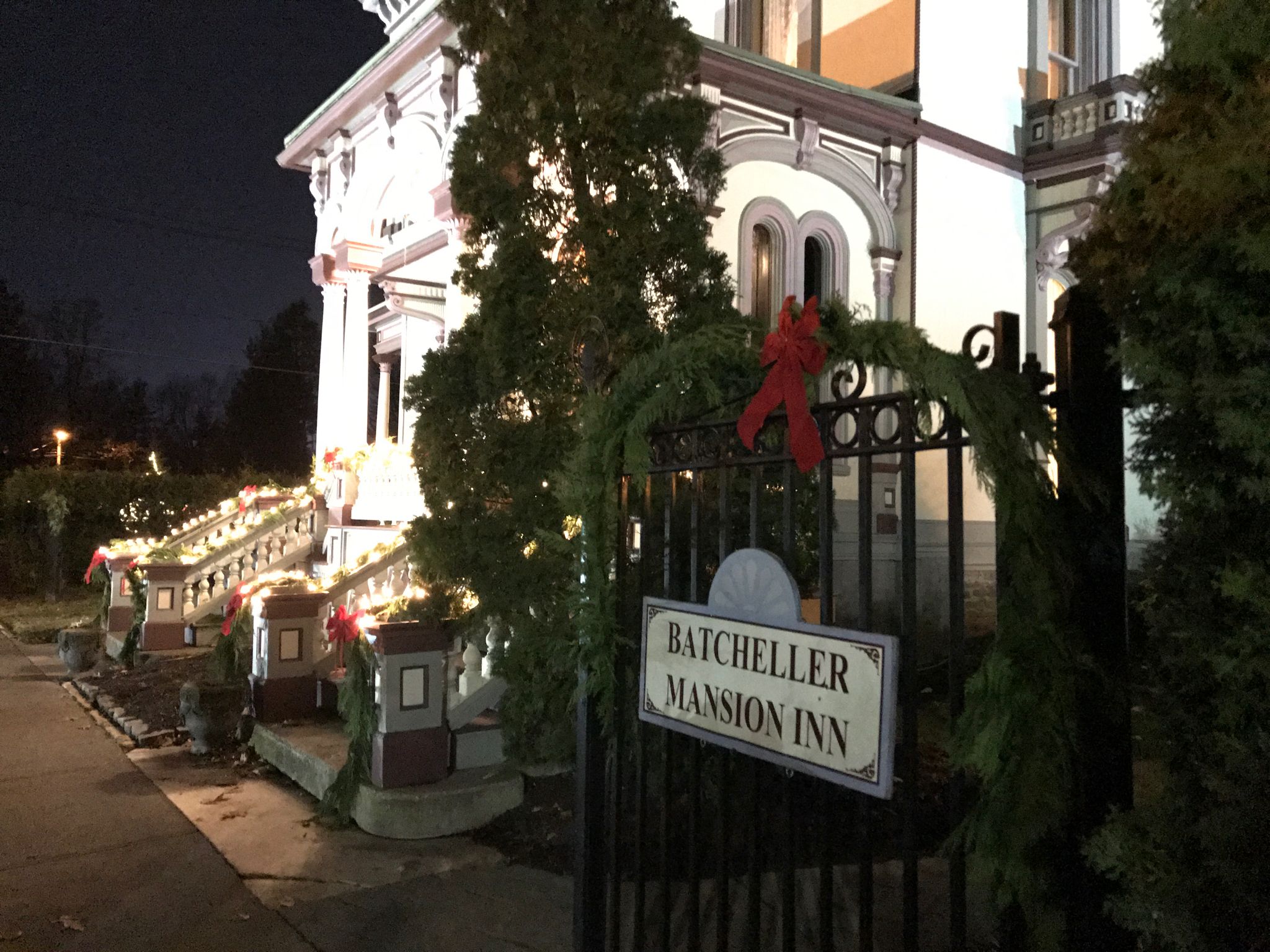 A gated entrance to Batcheller Mansion Inn with a sign.