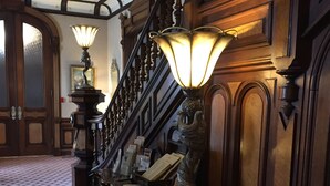 A grand staircase with ornate railings and a wooden finish, leading to a landing with a patterned carpet. - Batcheller Mansion Inn (Saratoga Springs)