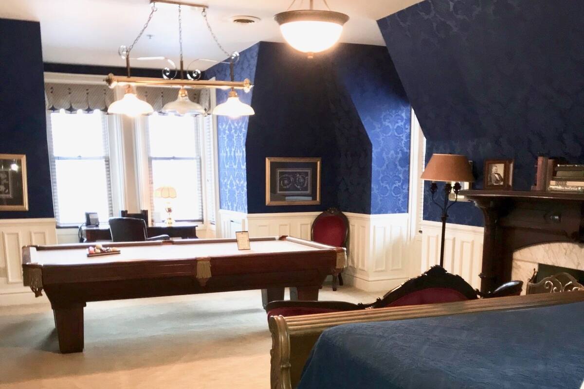 A room with a pool table, a bed, and a chandelier.