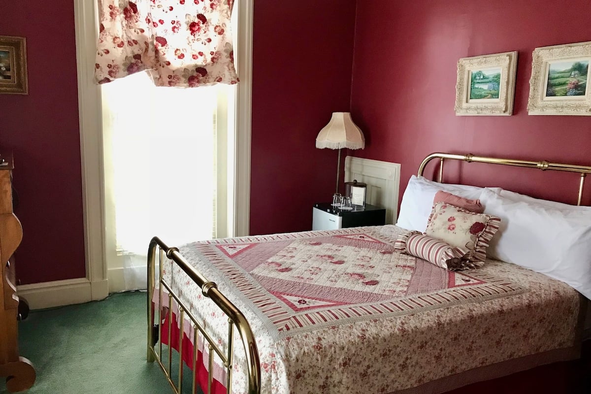A bedroom with a bed, a nightstand, a lamp, and two framed pictures on the wall.