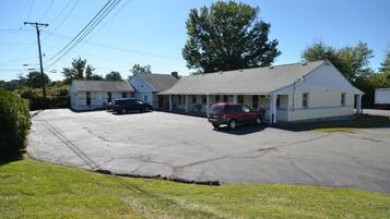 A two-story building with a parking lot, a red SUV, and a black car parked in front.