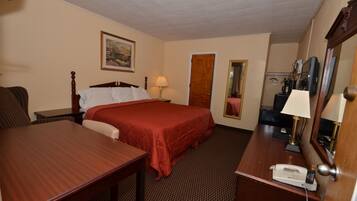 A hotel room with a bed, a desk, a telephone, a lamp, a mirror, and a painting on the wall.