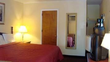 Una habitación de hotel con cama, escritorio, cafetera y espejo.