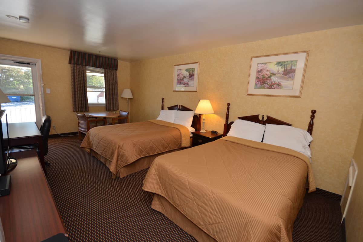 A hotel room with two beds, a desk, and a chair.