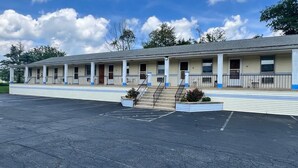 Un motel avec une rangée de chambres, une véranda et un parking.