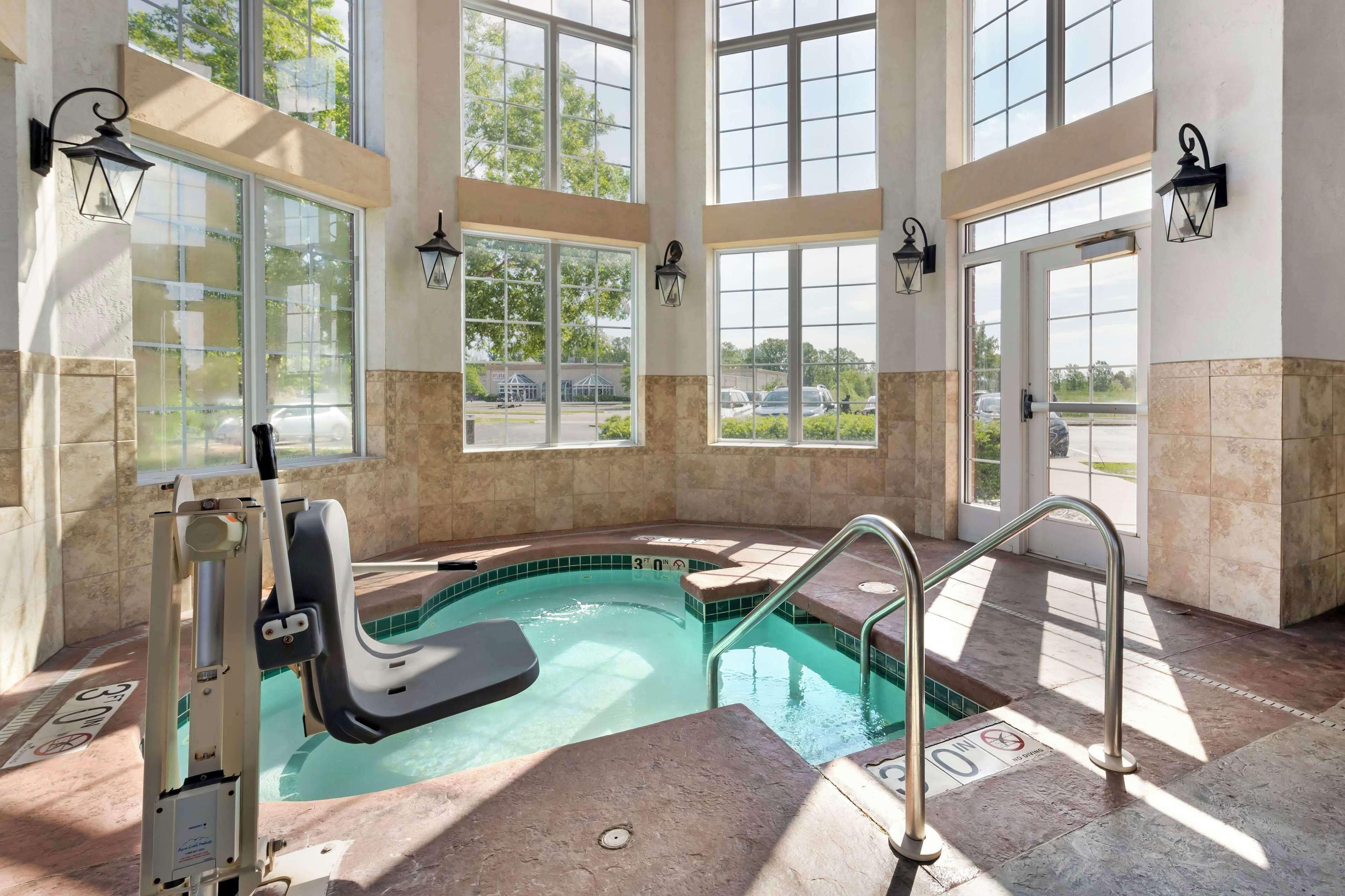 A pool area with a hot tub, clear glass windows, and a view of the outside.