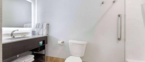 Une salle de bain avec des toilettes blanches, un lavabo avec un miroir et un espace douche.