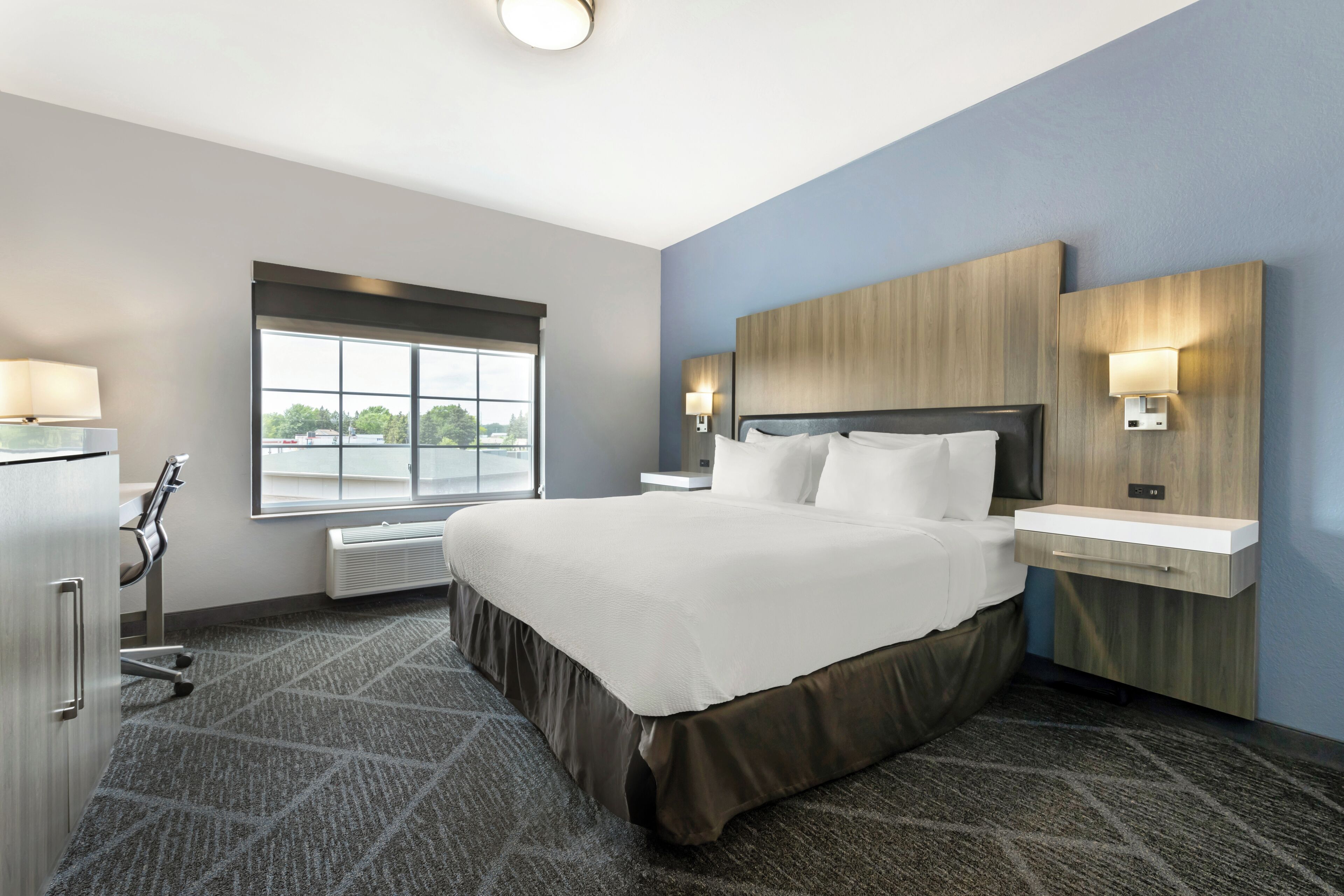 Hotelkamer met een groot bed, nachtkastjes, een bureau, een raam met uitzicht en een ingebouwde kachel.