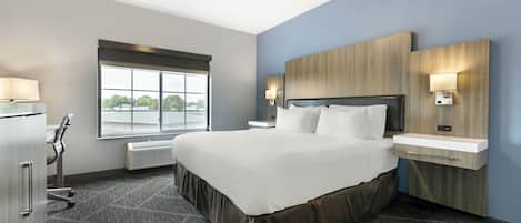 A hotel room with a large bed, bedside tables, a desk, a window with a view, and a built-in heater.
