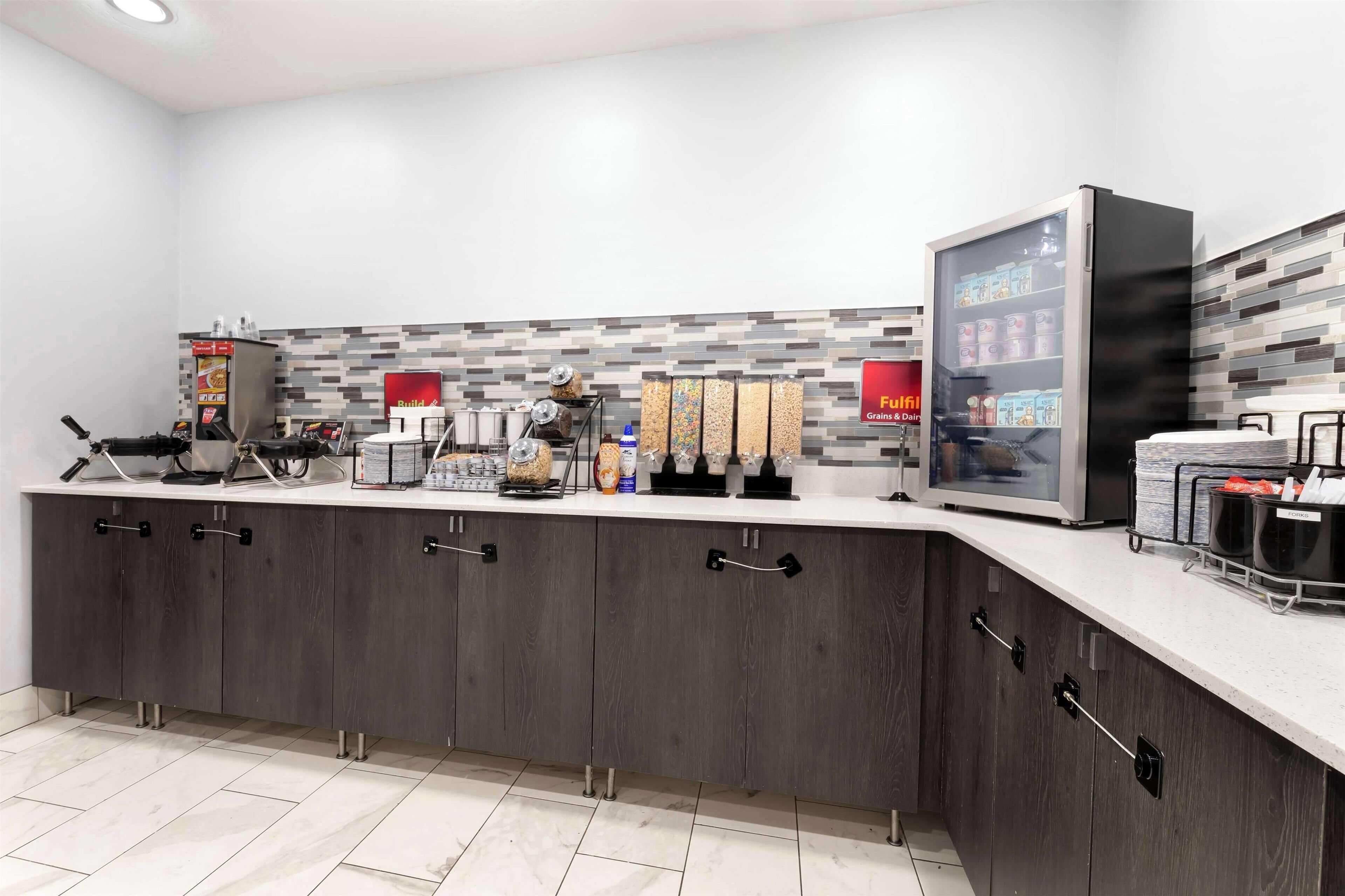 Una cocina moderna con cafetera integrada, un refrigerador lleno de bebidas y una encimera con diversos alimentos.