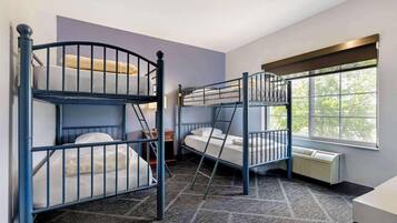 A room with bunk beds, a radiator, and a window with a view of trees.