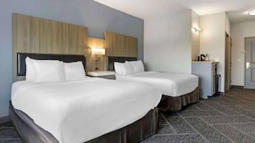 A hotel room with two beds, a small desk with a lamp, and a mirror above the bed.