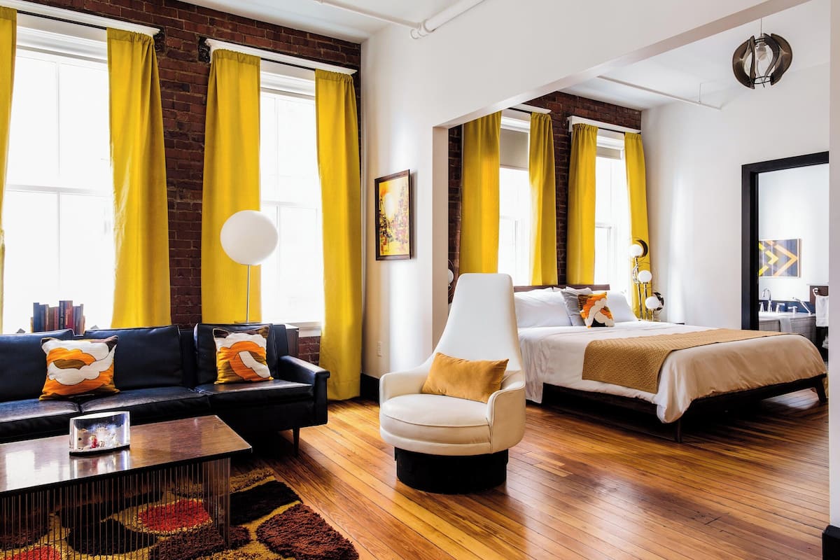 Ein modernes Hotelzimmer mit Sofa, Sessel und Bett.