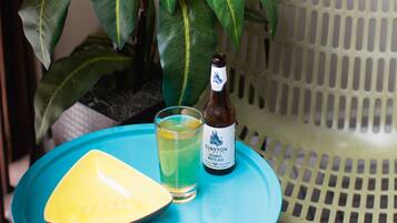 A small table with a bottle of beer and a glass of beer, a yellow plate, and a potted plant.