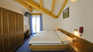 A bedroom with a wooden ceiling, a bed, a desk, and a chair. - Cristallo (San Giovanni di Fassa)