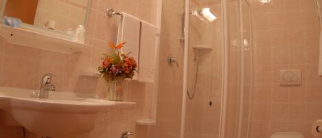 Une salle de bain équipée d’un lavabo, de toilettes, d’une douche et d’un petit tabouret.