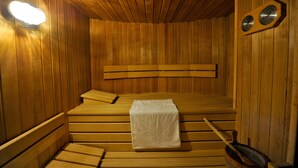 A wooden sauna with benches, a towel, and a clock on the wall. - Cristallo (San Giovanni di Fassa)