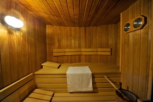 Una sauna de madera con bancos, una toalla y un reloj en la pared.