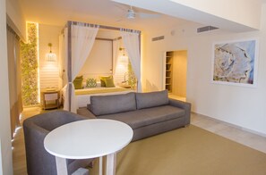 A modern living room with a grey sofa, a round white table, and a ceiling fan.
