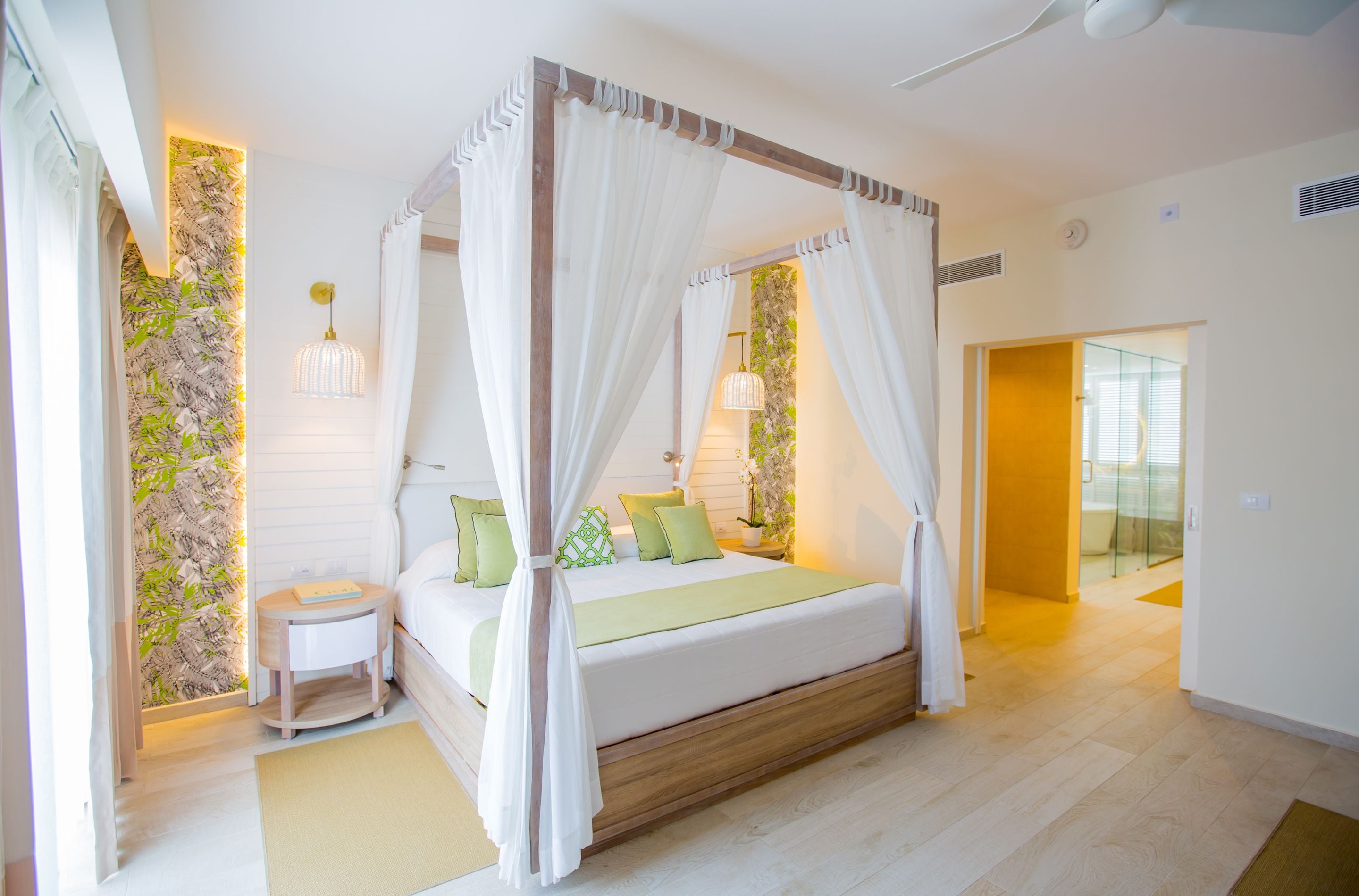 Un dormitorio con cama con dosel, una mesita de noche y un pequeño mueble auxiliar.