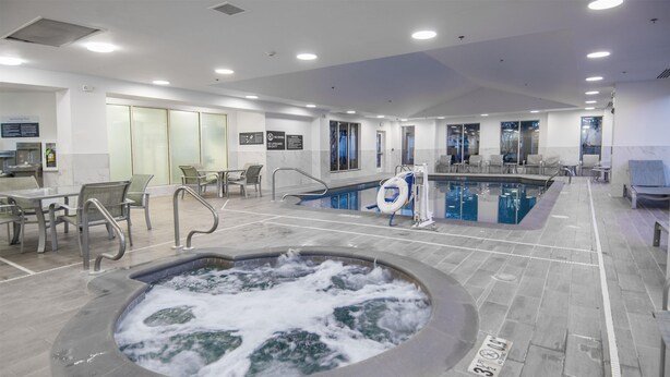A modern indoor pool area with a hot tub, seating, and a lifebuoy. - Hilton Garden Inn Hattiesburg (Hattiesburg)