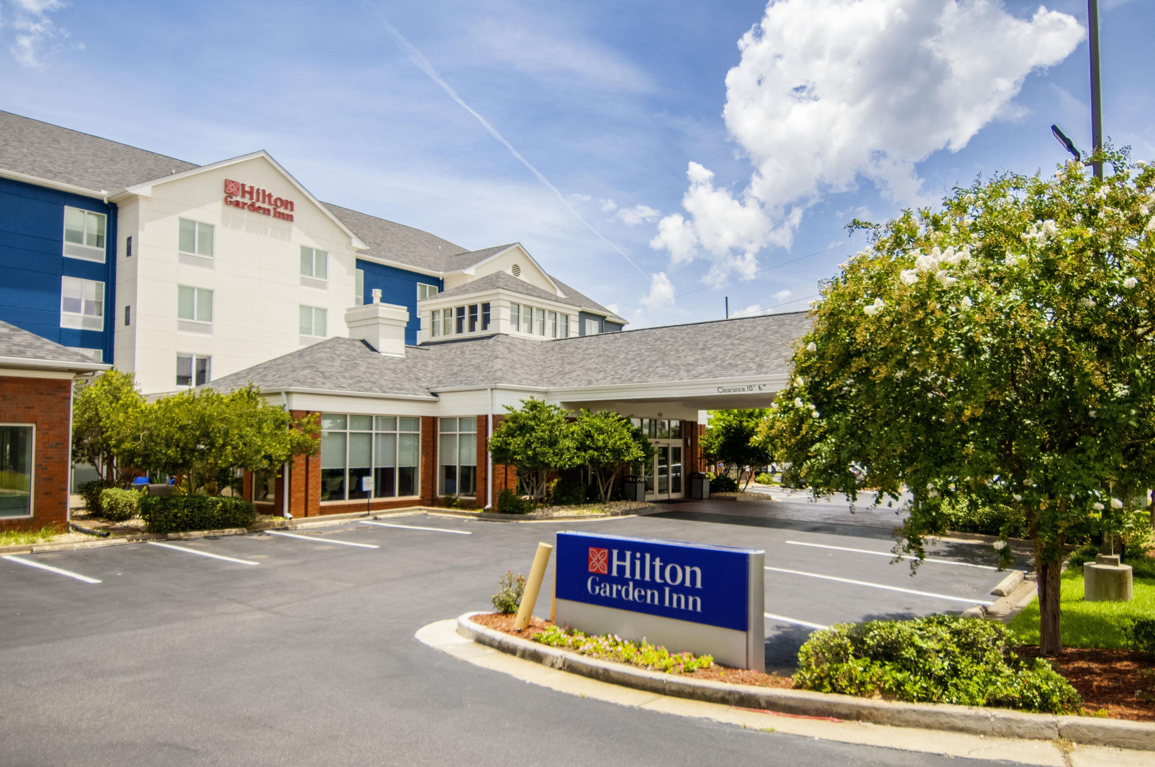 Un Hilton Garden Inn con cielo sereno, parcheggio e insegna con il nome dell'hotel.