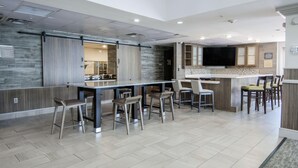 A modern kitchen with a central island, bar stools, and a flat-screen TV. - Hilton Garden Inn Hattiesburg (Hattiesburg)