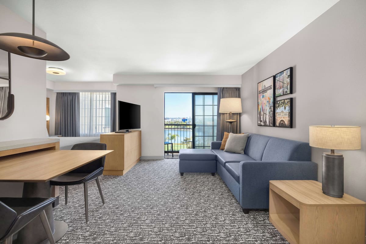 Une chambre d’hôtel moderne dotée d’un coin repas, d’un canapé, d’une télévision et d’un balcon avec vue.