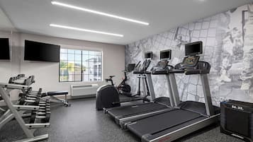 Un gimnasio con cintas de correr, bicicletas estáticas y máquinas de pesas.