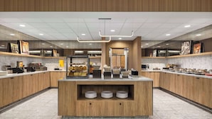 Cozinha moderna com armários de madeira, bancadas de mármore e uma ilha central com pratos.