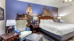 A hotel room with a large bed, a chair, a small table, and a nightstand. - Clarion Pointe Sulphur Springs (Sulphur Springs)