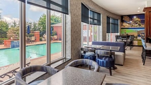 A hotel lobby with a pool view, seating areas, and a mural. - Clarion Pointe Sulphur Springs (Sulphur Springs)