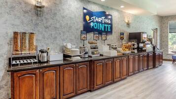 Una barra de desayuno con un letrero de Starting Pointe, una máquina de café y diversas opciones de comida.