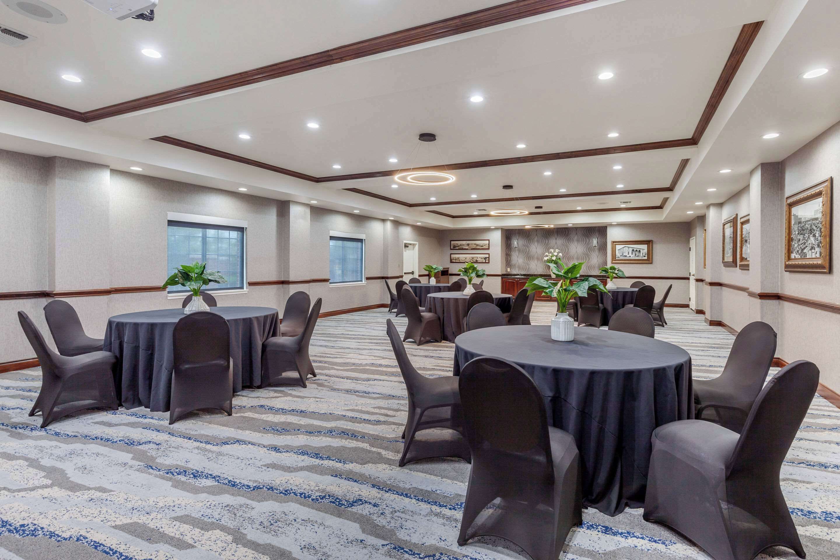 A conference room with round tables, chairs, and potted plants.