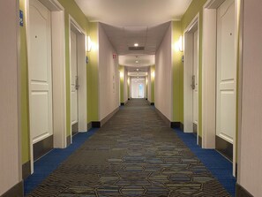 A hotel corridor with carpeted floors, doors on both sides, and overhead lighting. - Holiday Inn Express & Suites Beaumont - Oak Valley by IHG (Beaumont)