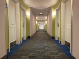 Un pasillo de hotel con pisos alfombrados, puertas a ambos lados e iluminación en el techo.