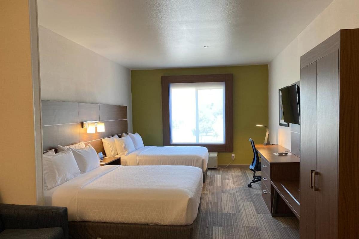 Habitación de hotel con dos camas, televisión, escritorio y ventana.