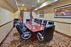 A conference room with a long table, multiple chairs, an American flag, and a painting on the wall. - Holiday Inn Express & Suites Beaumont - Oak Valley by IHG (Beaumont)